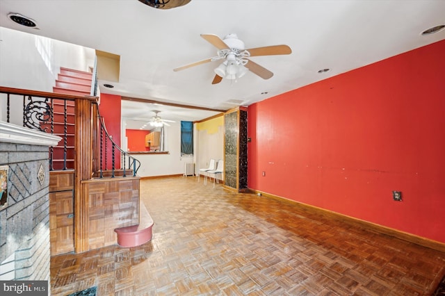 living room featuring ceiling fan, radiator heating unit, a fireplace, and parquet floors