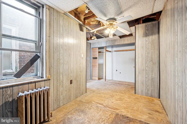 hallway with radiator and wood walls