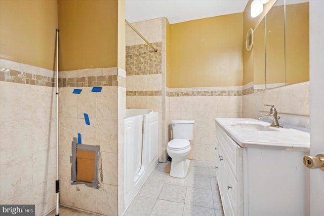 bathroom featuring tile walls, vanity, tile patterned flooring, and toilet