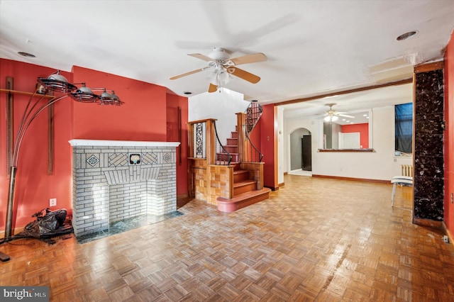 living room featuring a brick fireplace, parquet floors, and ceiling fan