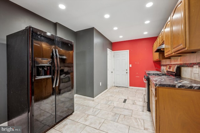 kitchen featuring black fridge, dark stone counters, gas range, and decorative backsplash