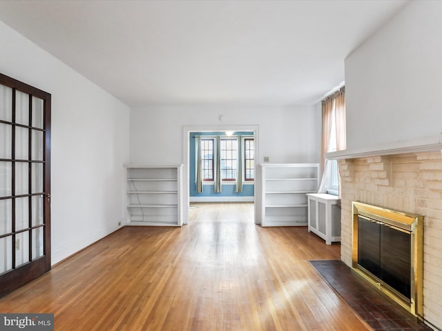 unfurnished living room featuring hardwood / wood-style flooring, a fireplace, and radiator