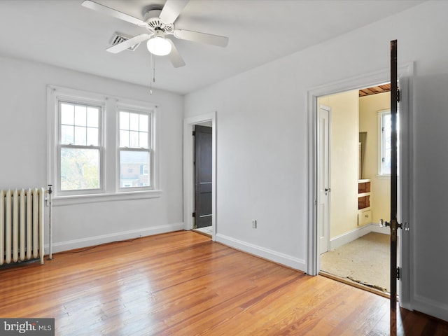 unfurnished bedroom with ceiling fan, radiator heating unit, and light wood-type flooring