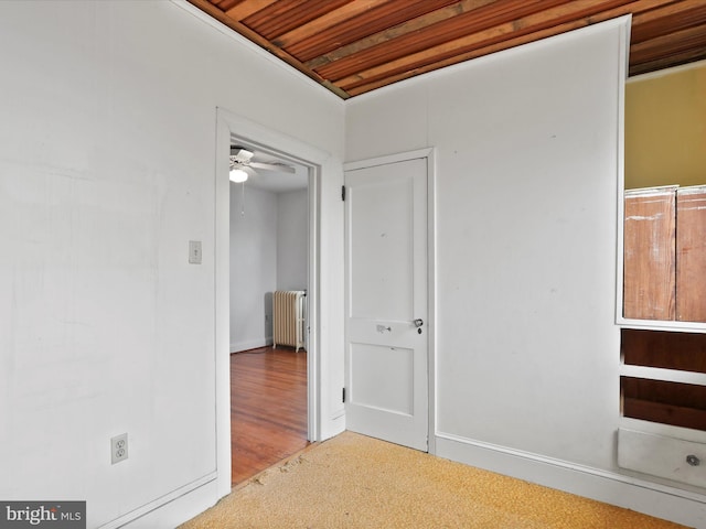 carpeted empty room with radiator, wooden ceiling, and ceiling fan