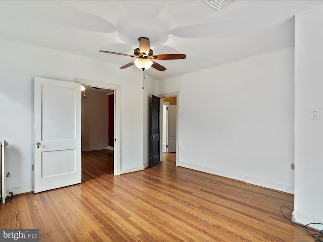 unfurnished bedroom featuring ceiling fan, radiator heating unit, and light wood-type flooring