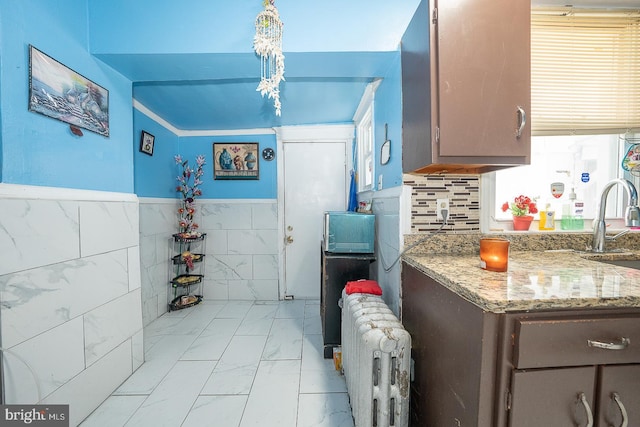 kitchen featuring stone counters, radiator heating unit, sink, tasteful backsplash, and pendant lighting