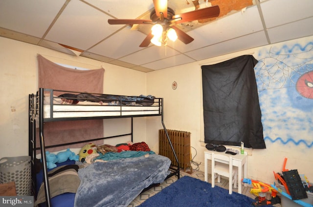 bedroom featuring radiator heating unit, a drop ceiling, and ceiling fan