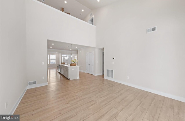 unfurnished living room with a towering ceiling and sink