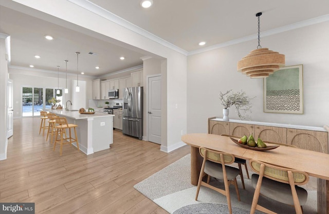 kitchen featuring appliances with stainless steel finishes, a kitchen island with sink, pendant lighting, and white cabinets