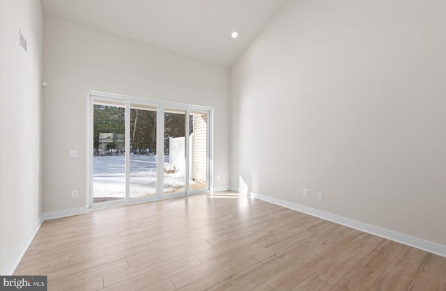 spare room with light hardwood / wood-style flooring and high vaulted ceiling