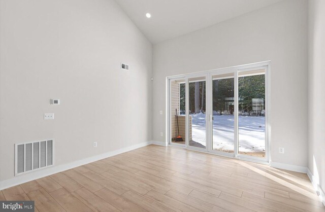 unfurnished room featuring high vaulted ceiling and light hardwood / wood-style floors