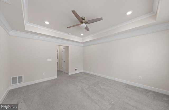 carpeted empty room with a raised ceiling, ceiling fan, and crown molding