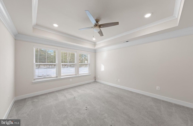 spare room featuring ceiling fan, a tray ceiling, crown molding, and light colored carpet