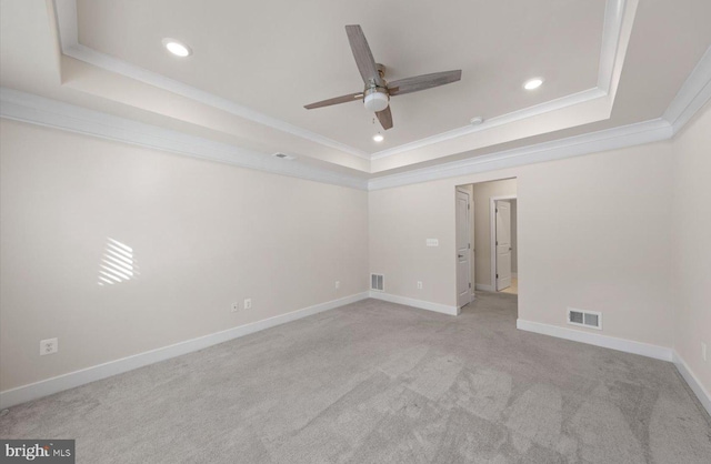 carpeted empty room with ceiling fan, ornamental molding, and a tray ceiling