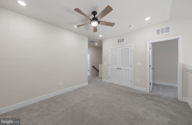 unfurnished bedroom featuring vaulted ceiling, light colored carpet, ceiling fan, and a closet