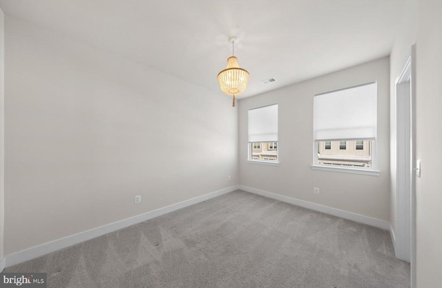 spare room featuring a notable chandelier and carpet