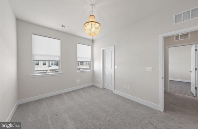 unfurnished room featuring light colored carpet and a chandelier