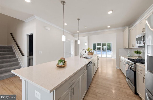 kitchen featuring decorative light fixtures, stainless steel appliances, a center island with sink, tasteful backsplash, and sink