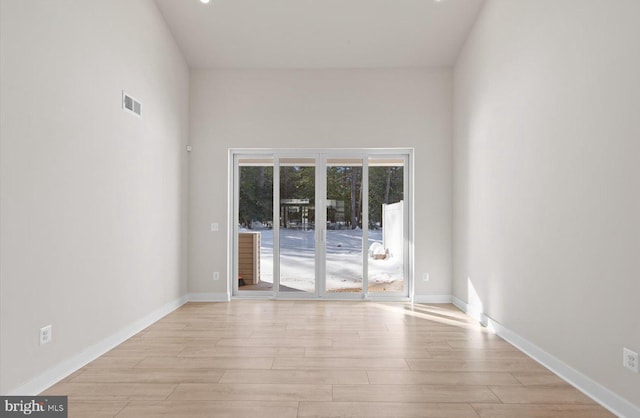 empty room featuring a high ceiling and light wood-type flooring