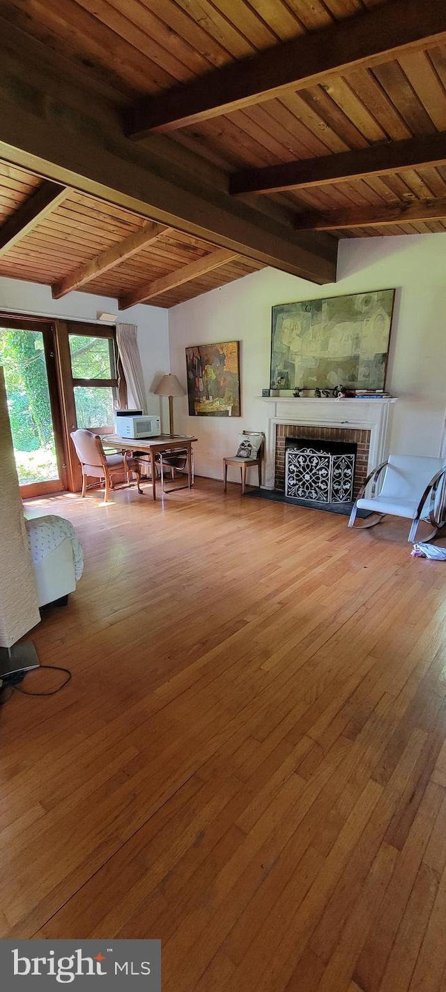 unfurnished living room featuring a brick fireplace, beam ceiling, wood-type flooring, and wooden ceiling