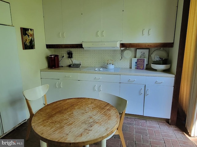 kitchen featuring refrigerator, backsplash, range hood, and cooktop