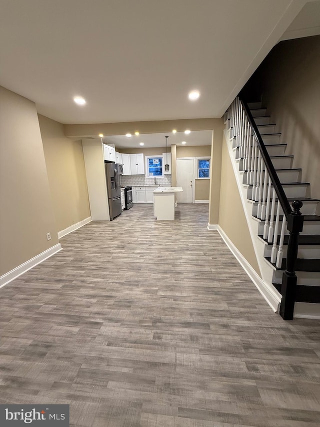 unfurnished living room featuring sink and light hardwood / wood-style flooring