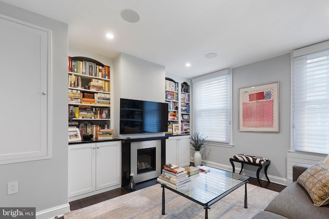 living room featuring dark hardwood / wood-style flooring, built in features, and a wealth of natural light