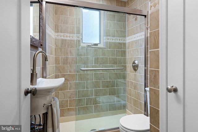 bathroom featuring toilet and a shower with shower door