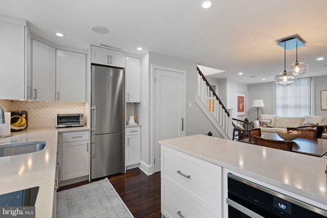 kitchen featuring stainless steel refrigerator with ice dispenser, tasteful backsplash, sink, white cabinets, and hanging light fixtures