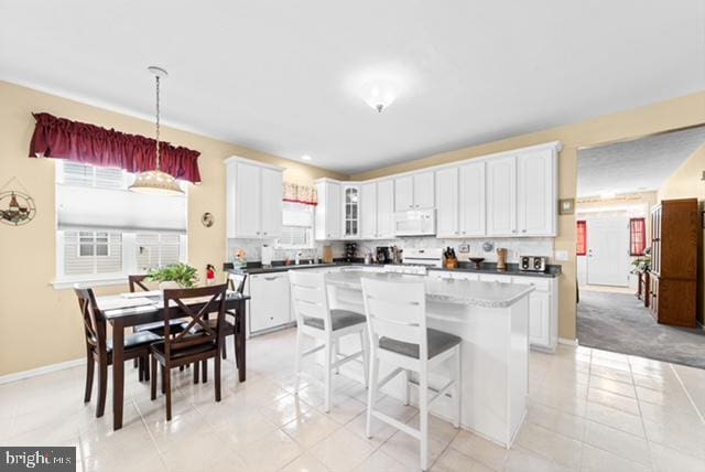 kitchen featuring white cabinetry, light tile patterned floors, decorative light fixtures, and white appliances