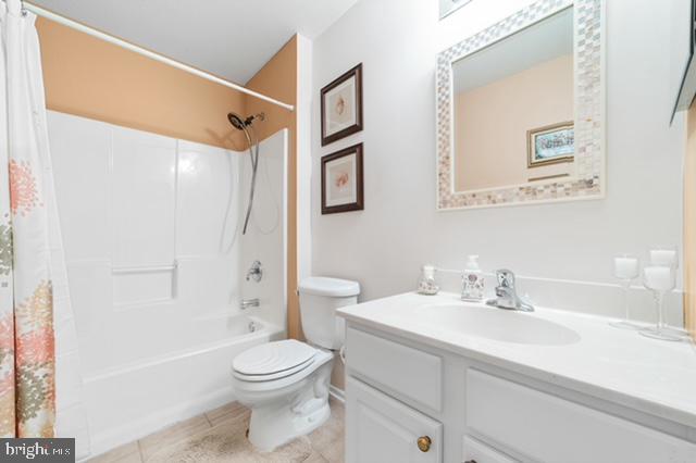 full bathroom with shower / bathtub combination with curtain, tile patterned flooring, vanity, and toilet