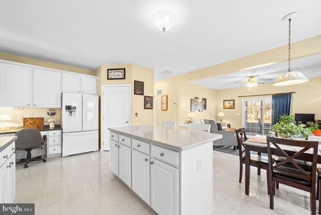 kitchen with white refrigerator with ice dispenser, white cabinetry, and hanging light fixtures