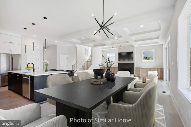 dining area featuring coffered ceiling, sink, beamed ceiling, a chandelier, and plenty of natural light