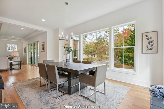 dining space with light hardwood / wood-style flooring and an inviting chandelier