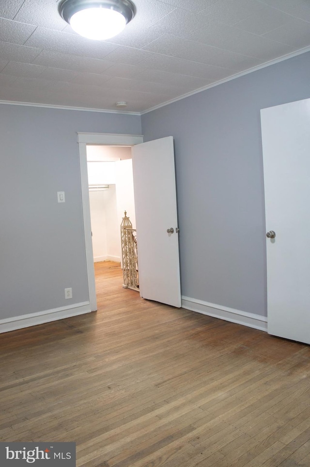 unfurnished room featuring wood-type flooring and crown molding