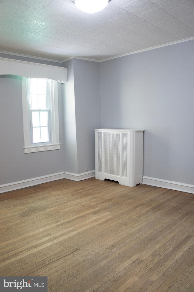 unfurnished room with hardwood / wood-style floors and crown molding