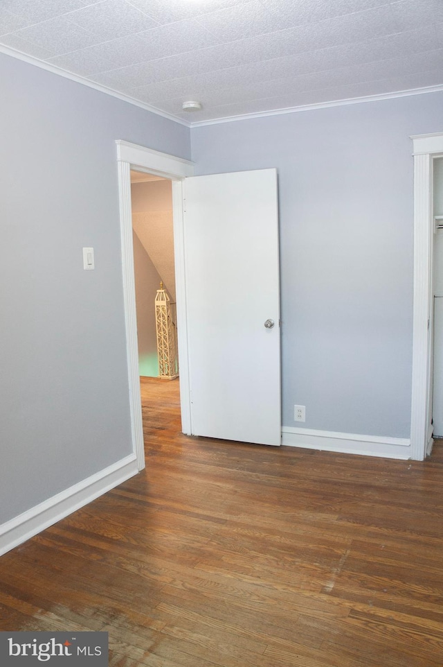 empty room with a textured ceiling, dark hardwood / wood-style floors, and crown molding