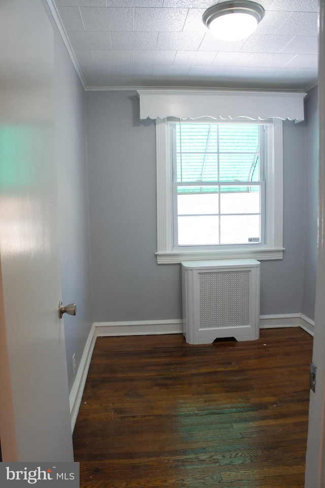 spare room with dark hardwood / wood-style flooring, radiator heating unit, and ornamental molding