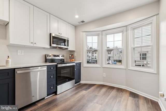 kitchen with white cabinetry, hardwood / wood-style floors, and appliances with stainless steel finishes