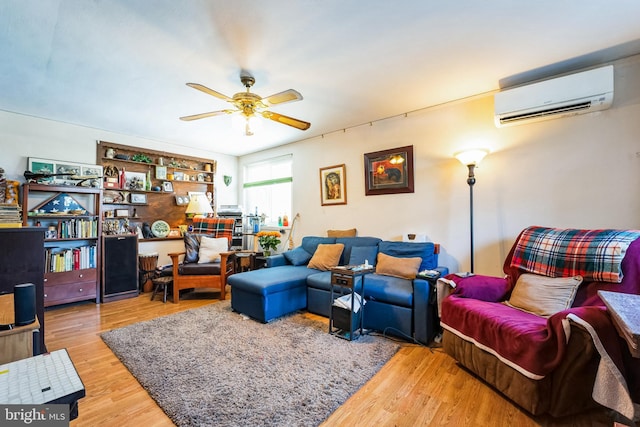 living room featuring a wall mounted air conditioner, wood-type flooring, and ceiling fan