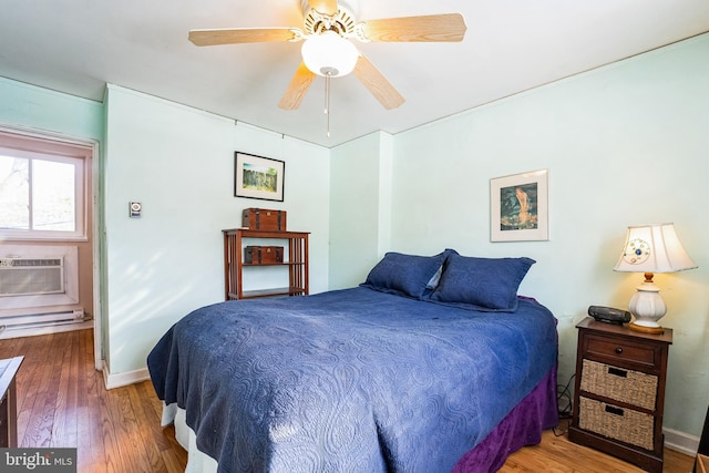 bedroom with a wall unit AC, ceiling fan, and wood-type flooring