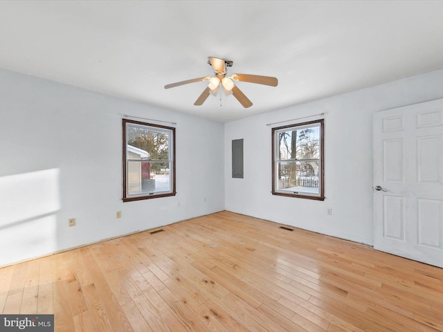 empty room featuring ceiling fan, light hardwood / wood-style floors, and electric panel