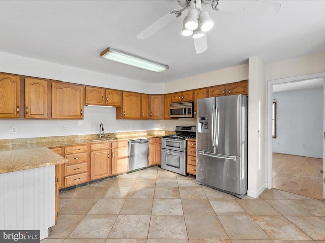 kitchen with ceiling fan, sink, light tile patterned floors, and stainless steel appliances