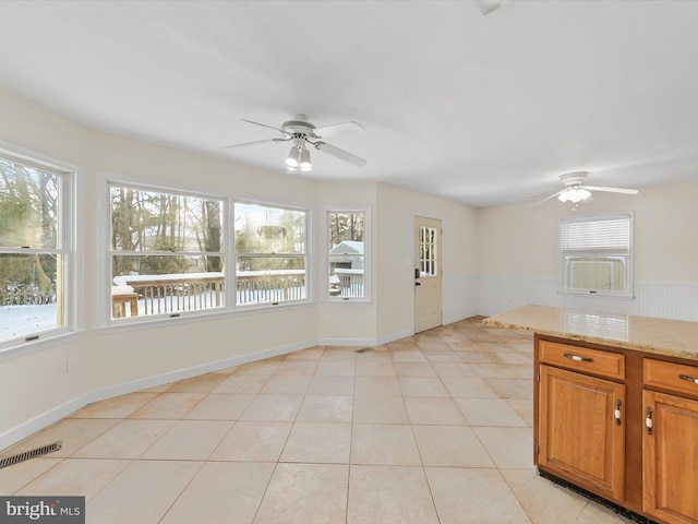 kitchen with ceiling fan, light stone counters, and light tile patterned floors