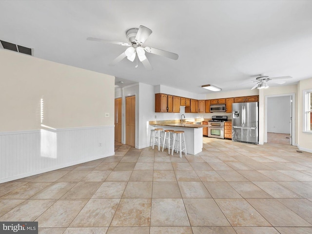 kitchen featuring sink, light tile patterned floors, a kitchen bar, kitchen peninsula, and stainless steel appliances