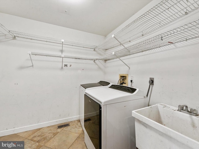 laundry room with washer and clothes dryer, sink, and light tile patterned floors