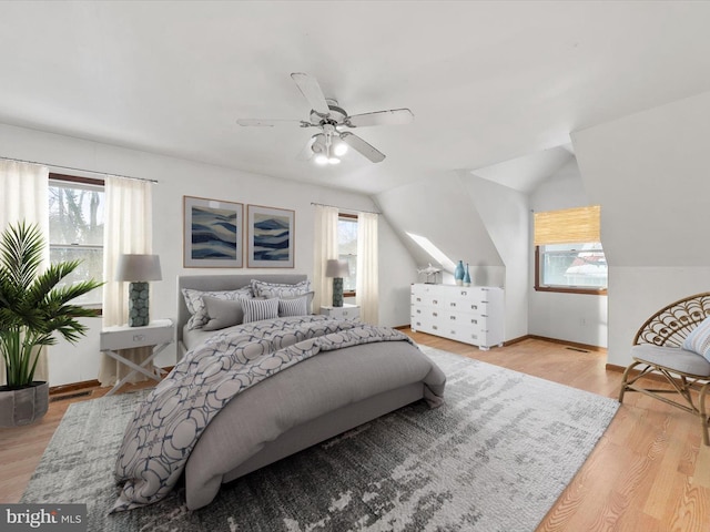 bedroom with ceiling fan, vaulted ceiling, light wood-type flooring, and multiple windows