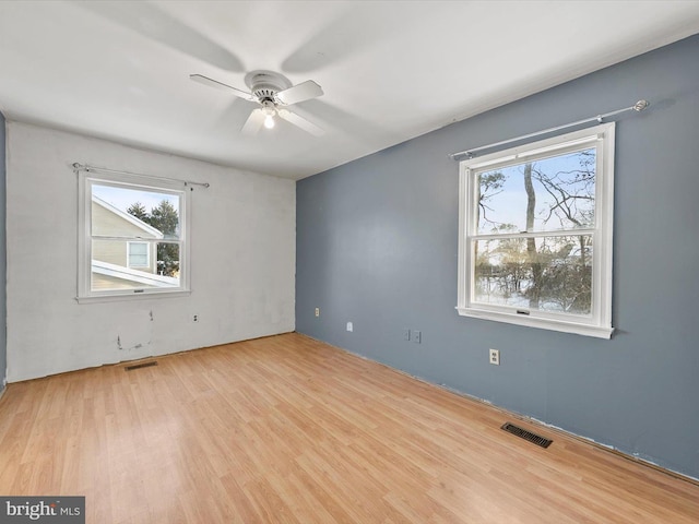 empty room featuring light wood-type flooring, ceiling fan, and a healthy amount of sunlight