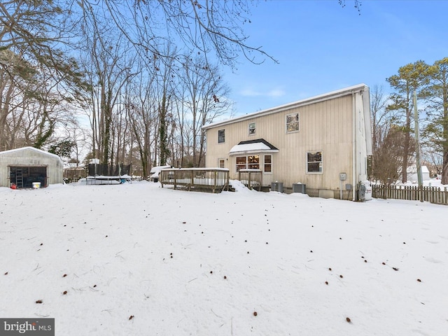 snow covered house with an outbuilding, a wooden deck, and central air condition unit