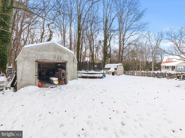 snowy yard with a storage shed and a trampoline